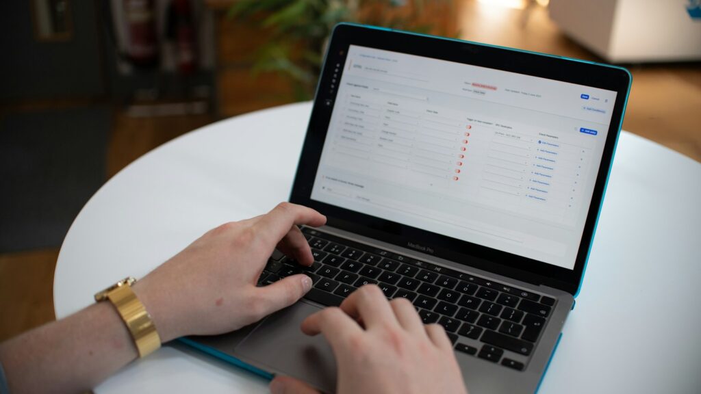 Hände tippen auf einem Laptop mit Tabelle – KI-Agenten übernehmen Routineaufgaben im Büro