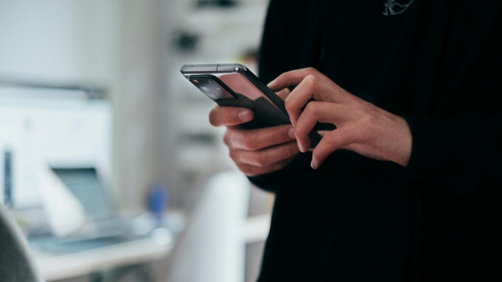Person hält ein Smartphone in der Hand, um den Kundenservice zu kontaktieren