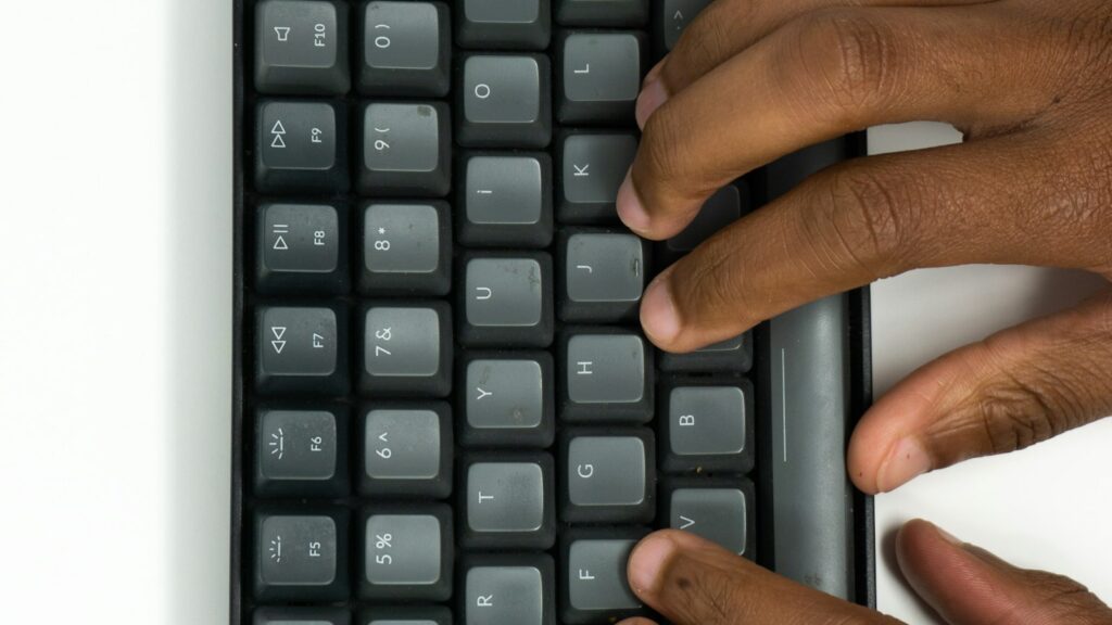 Hände auf einer Tastatur beim Prompts schreiben für einen KI-Assistenten