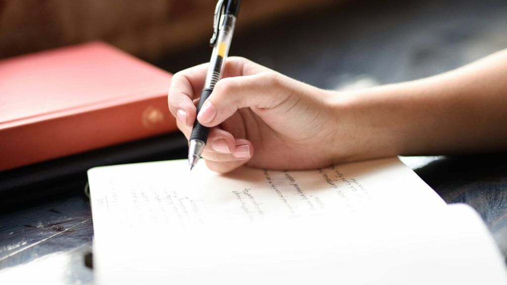 Person notiert mit einem Stift Gedanken auf einem Blatt Papier