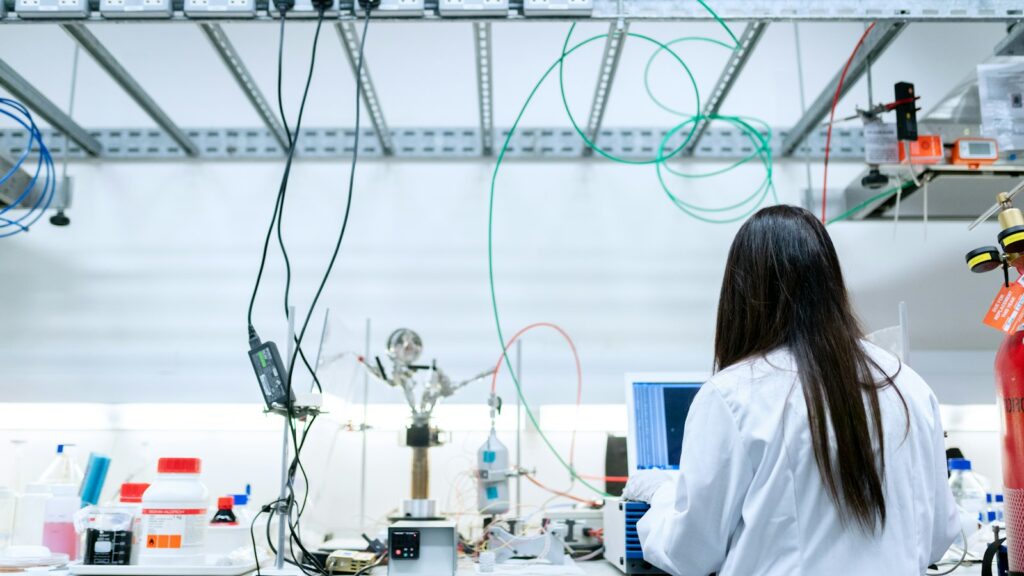 Wissenschaftlerin im Laborkittel arbeitet am Laptop im Labor