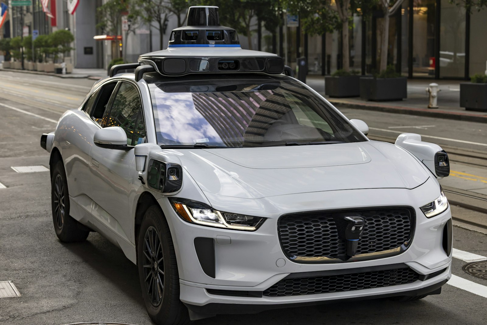 Robotaxis: Weißes selbstfahrendes Auto mit Sensoren auf einer Stadtstraße