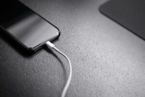 Smartphone-Akku: Schwarzes Smartphone mit angeschlossenem Ladekabel