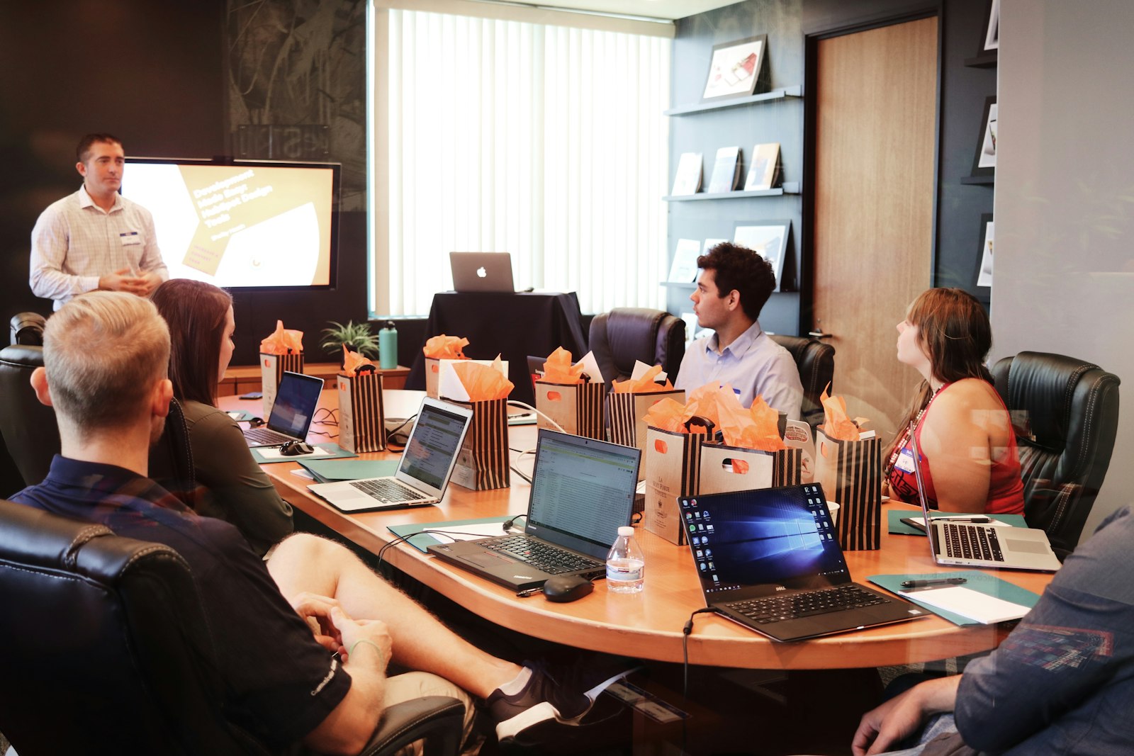 Team bespricht sich an einem Tisch mit Laptops