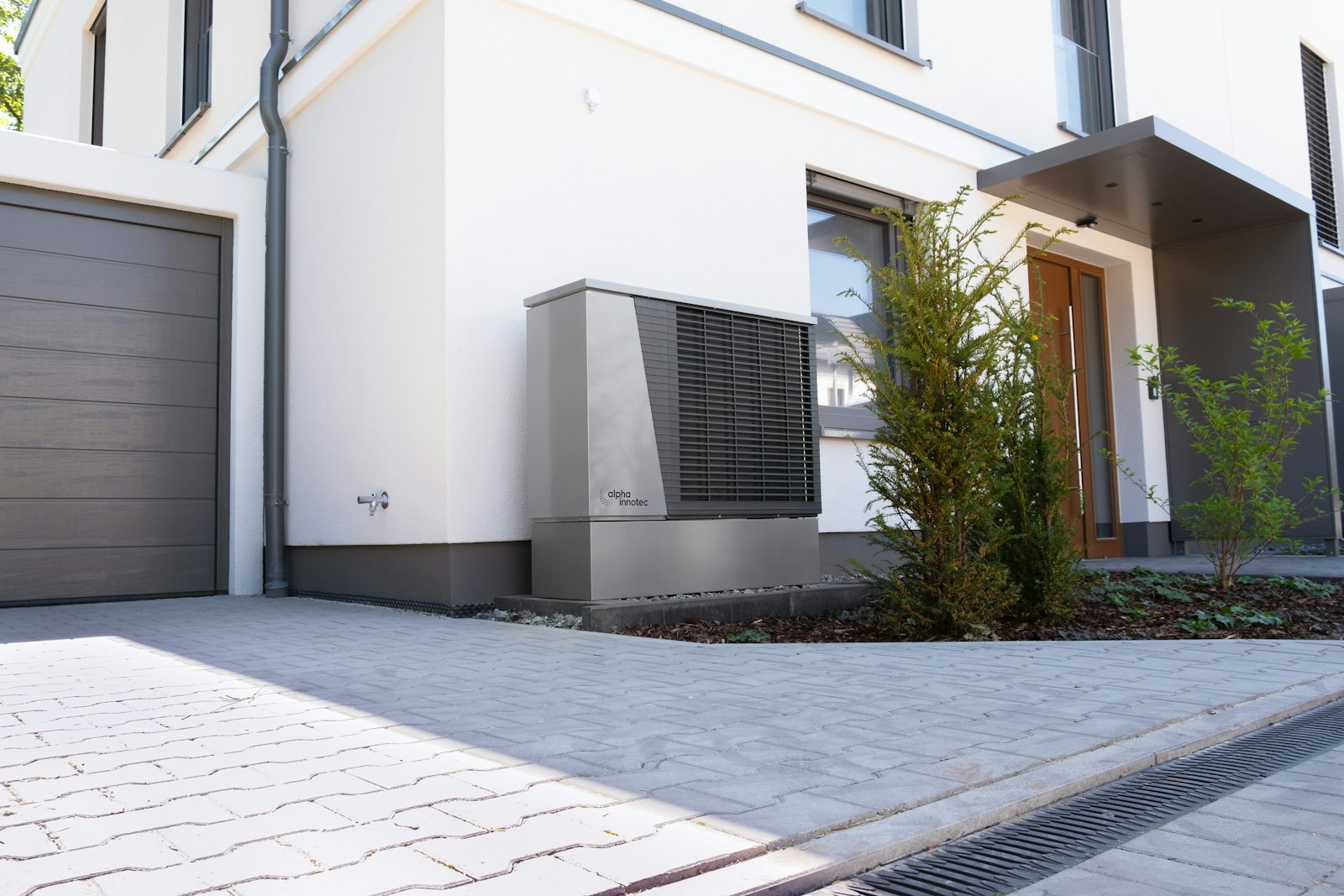 Wärmepumpe steuern: Außeneinheit einer Wärmepumpe vor einem modernen Haus
